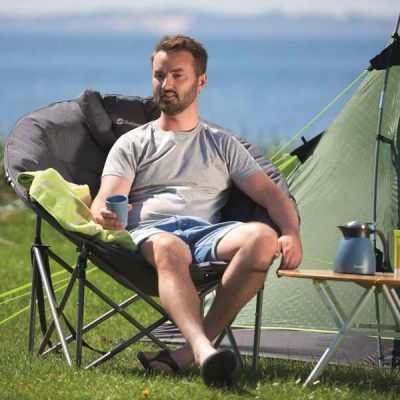 Man relaxing in a campchair holding a cup of coffee.